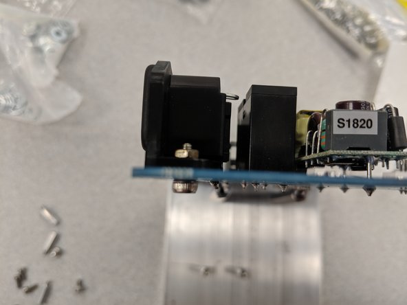 The last step in preparing the PCB is to secure the 110 VAC power entry (in) and egress (out) to the board even further with screws and nuts.  This will ensure they can withstand the forces of cords being inserted and removed.