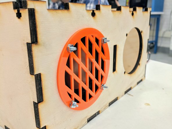 Place one speaker INSIDE the box on the left side.  Rotate the speaker so that the four mounting holes align with the holes in the panel and so that the wires soldered to the speaker are on the right side.   Press the rubber gasket flush against the front panel.