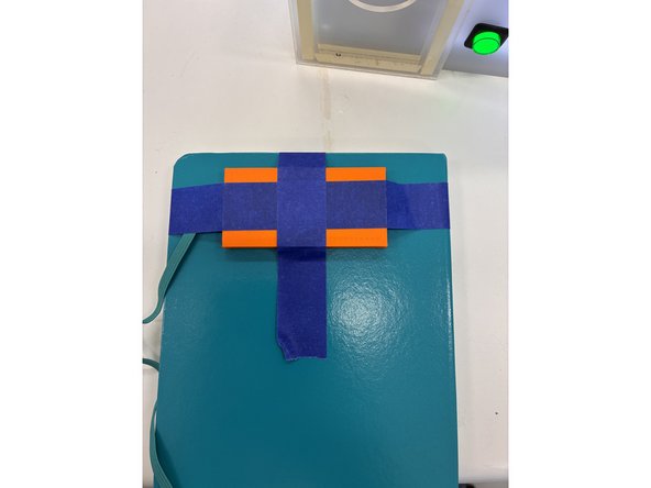Put the embossing stamp on the journal where you want it then hold it down with blue painter’s tape so it won’t move as shown in the first image.