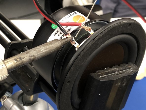 Gently place your speaker in a vice.  Locate the two metal tabs near the front of the cone of the speaker.