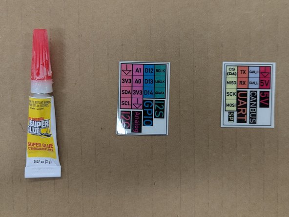 Locate the two laminated labels.  Place them on top of some scrap cardboard, plywood, paper towel, etc.  You should not perform this step directly on a bench or table!