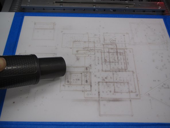 Get the vacuum from the cabinet to the right of the yellow DeWalt tool chest. Use the vacuum to thoroughly clean the white milling bed surface.