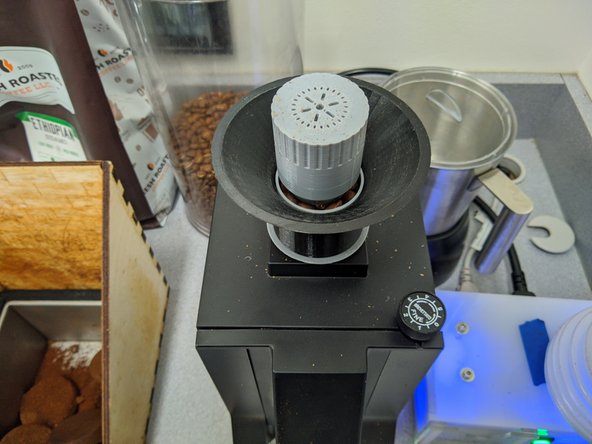 Now place the gray plastic topper on top of the beans.  This ensures the beans don't &quot;popcorn&quot; during single dose grinding and fly out of the grinder.