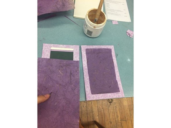 Lightly coat the end papers with glue and stick them over the cardboard cutouts.