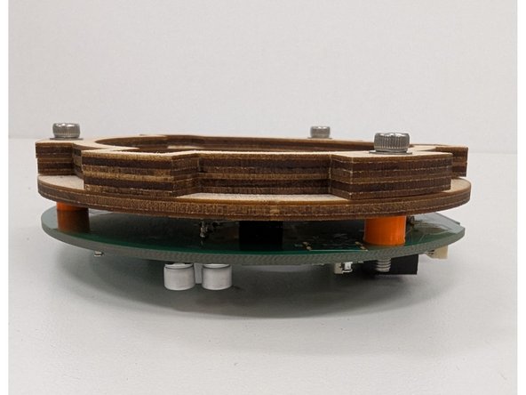 Carefully place the plywood stack on top of the PCB, aligning the bolts with the plastic spacers.  The bolts should pass through the plastic spacers and protrude from the front side of the PCB.