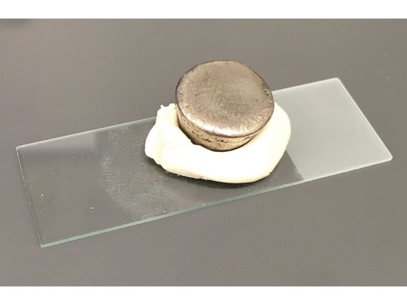 Secure polished material samples to a slide glass with a bit of modeling clay.