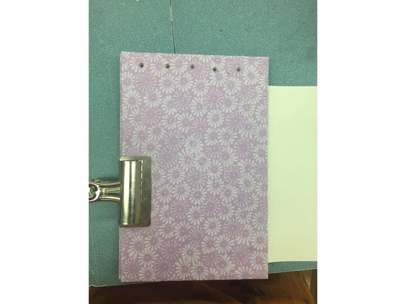 This is how your journal should look like after drilling the holes. Now, leave the binder clip and tie string through the holes.