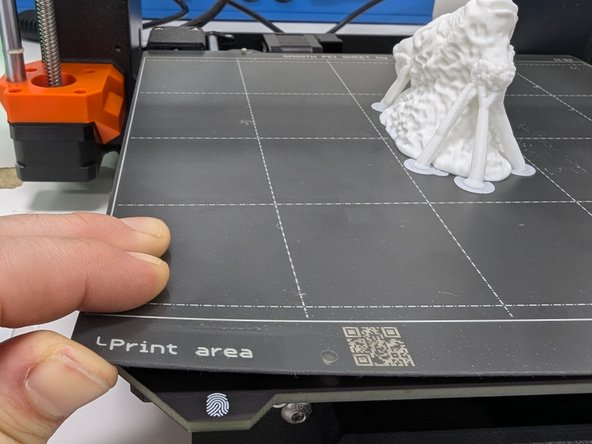 When your print is complete the printer will move the bed forward and move the print head up out of the way.  You should carefully lift a front edge of the metallic print surface to completely detach it from the magnetic bed.