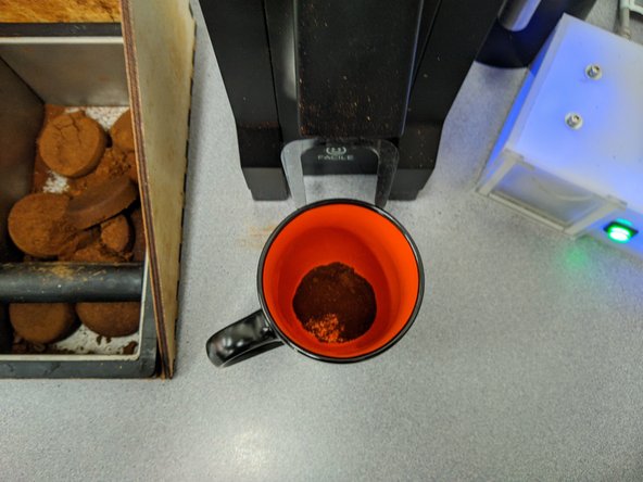 Hold an empty cup under the grinder spout to catch grounds.  Pump the bellows firmly several times.