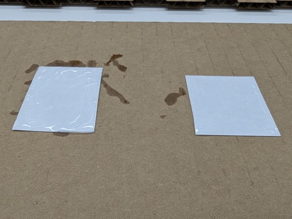 Flip the labels over to the blank white backs.  Grab a tube of super glue from on top of the yellow DeWalt cabinet in the Maker-E.  Apply a small amount of super glue to back of the labels.  Make sure you spread it around the edges of the labels so they won't peel.  Smear the glue off the edge onto the protective surface you have underneath.