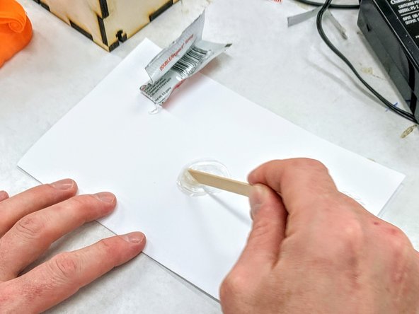Cut the top off of the epoxy packet.  Squeeze the contents of both sections onto the index card.  Use the popsicle stick to completely mix the two parts of the epoxy until it turns somewhat white.