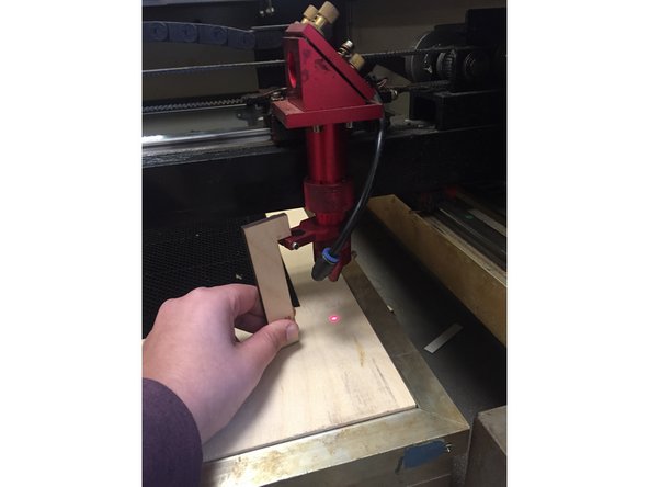 Take the focal length tool located in the red box on the laser cutter and position it on the ledge of the laser with the long part of it's "L-shape" towards your material and the short end parallel to the bed.