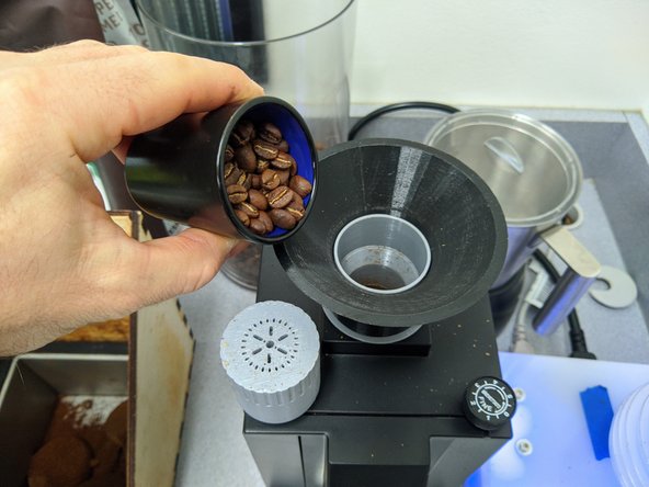 Place the black plastic funnel on top of the grinder and be sure to remove the gray plastic topper.  Pour beans into the funnel and ensure they are all in the grinder chamber.