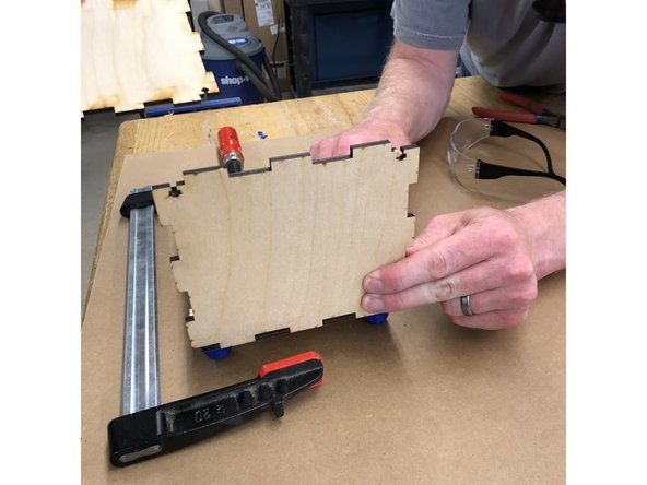 Take one of your short side pieces.  The top always has the &quot;keyhole&quot; cut out.  Select which side you want to face outwards.  On the other side, paint wood glue onto the ends of the bottom teeth.