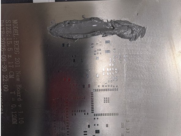 Using the popsicle stick, grab a blob of paste and apply it in a line across one side of the stencil. Make sure the paste is above all of the openings in the stencil.  Note in the image that we're applying the paste to a side and not the top of  bottom.  This is because our spreader is best suited for application in this direction.