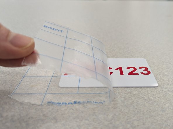 Using the blue lines on the tape to make sure the text remains horizontal, move your vinyl decal onto your card.