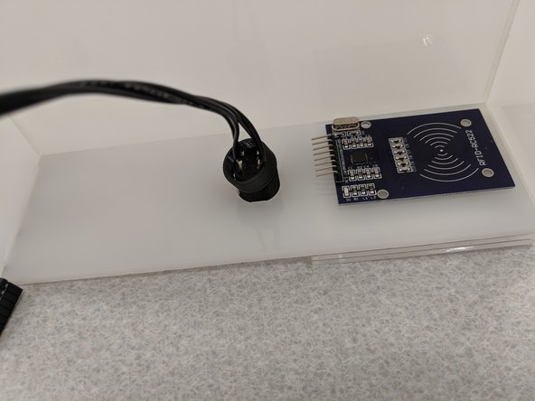 Unscrew the plastic nut from the pushbutton and thread the button through the hole on the front panel.