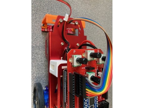 Use the 8-pin ribbon to connect the IR strip's sensors and the Arduino shield. The ribbon should not include the strip's pins for Vcc, Gnd, or LEDon, just the sensors 1 through 8. It should fit into the 8-pin shield header labeled &quot;IR sensors output&quot; with the wire for sensor 8 toward the back of the robot.