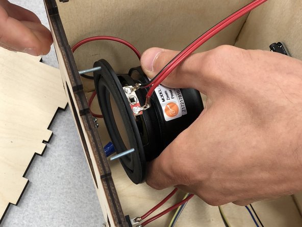 Put the grille on the front of the speaker. Use a screwdriver to hold the screws in place, and hand tighten the nuts.