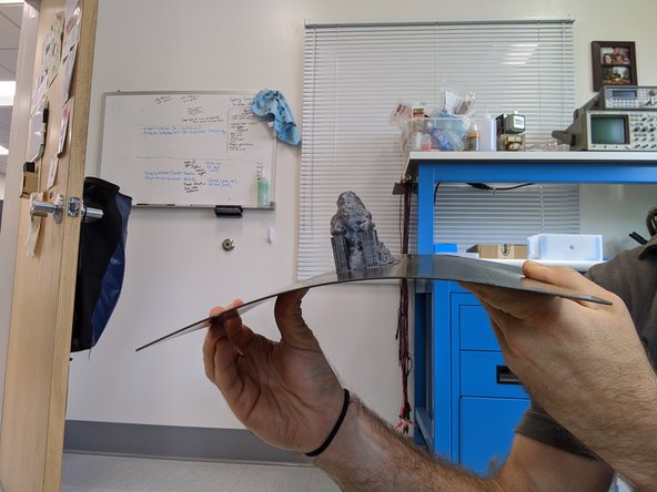 Be careful not to burn yourself, wait a couple minutes before completing this step. Hold down on the edge of the bed and pull magnetic print surface off.  Once the print surface (with your print) is removed from the printer then detach the print by gently flexing the print surface.