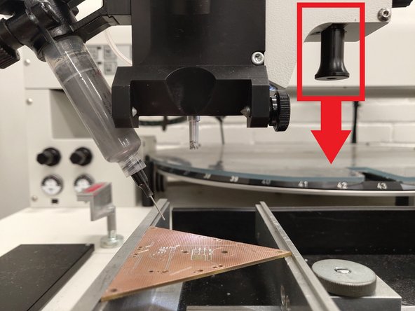 Now pull down on the black placement knob to slowly lower the tube.  Watch the nozzle tip in the monitor or at the PCB itself.  Confirm that the nozzle tip can just touch the surface of the PCB.  Be careful not to extend the head too far down and bend the tip.
