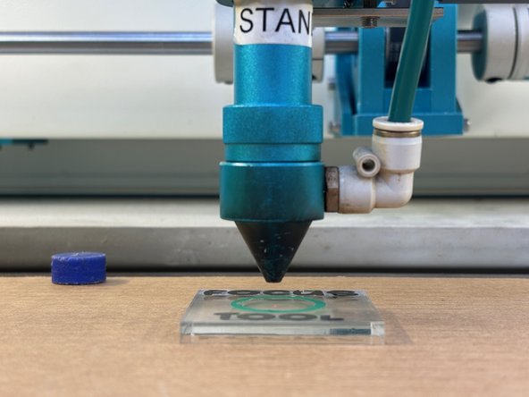 Use the arrow keys on the laser cutter interface (shown in green in a previous step) to move the laser head over the center of the focus tool.  You should see the red laser pointer dot hitting your material.