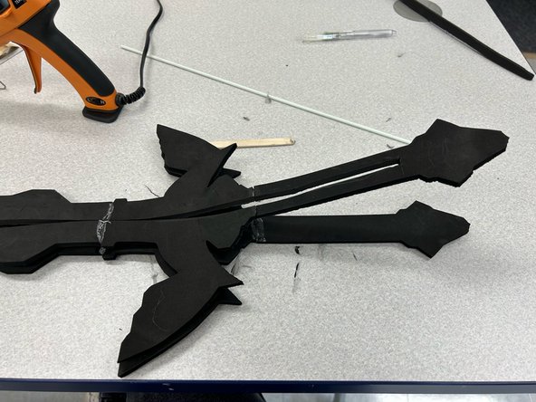 Glue the sword with the cut out to one of the other swords with hot glue. Work in sections and use a popsicle stick to spread out any excess glue