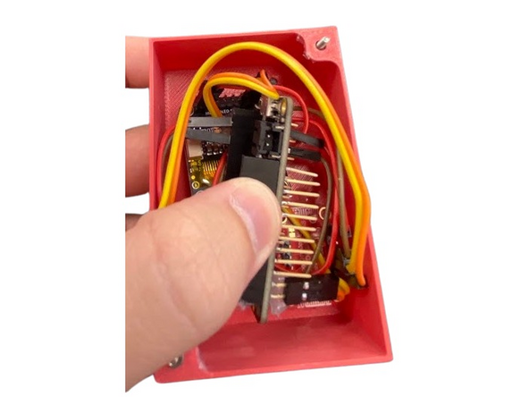 Now take two of your M2 screws/bolts and thread them out of the case from the inside on the two holes that go to the lid. Add a generous dab of hot glue to keep this in place. Since we can't get an allen key at their heads inside the case, these must stay stationary so we can thread a nut on the other side.