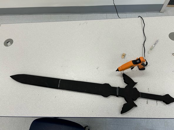 Glue the last piece of the sword on top of the piece with the rod, so that the rod is sandwiched between the layers of foam.