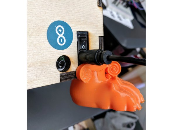 Flip the rocker switch, located above the power barrel jack, to the up position.  You should hear a chime.