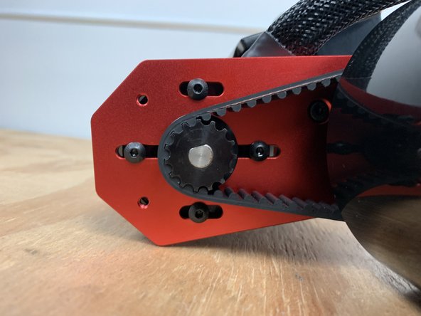 While holding tension in the belt tighten one bolt