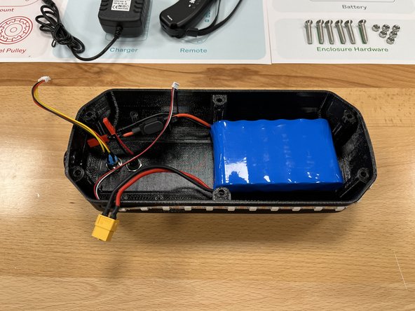 Place the battery inside the enclosure with the wires facing the switch and charge port