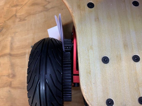 Place the piece of paper between the motor pulley and rim of the tire