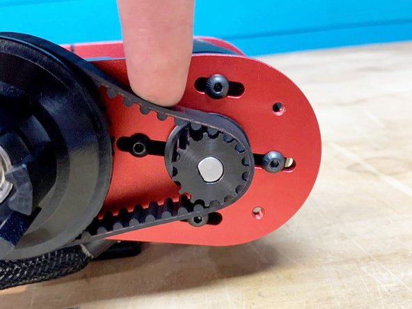 Put a small amount of pressure downwards on the belt. It should deflect slightly as shown in the 3rd photo