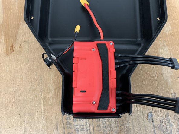 Slide the charge port through the hole in the left side of the enclosure