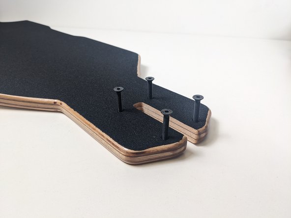 Remove any plastic and place the truck bolts through the mounting holes, press the bolts through the front of the deck.