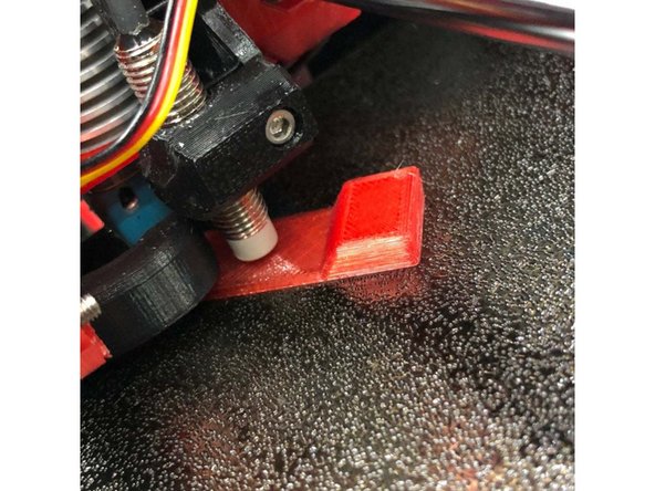 Place a piece of paper on print bed. Nozzle tip must be clean and printer powered off.