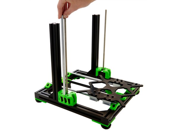 Place a z-rod in the hole next to the z-stepper motor on the z-motorholder . Carefully tap the z-rod straight into place.