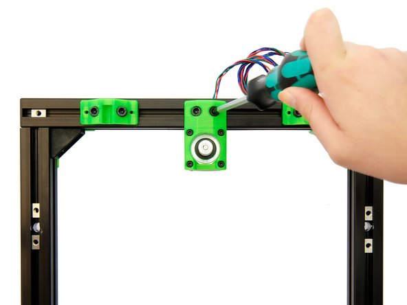 Befestigen Sie die zusammengebaute y-Motorhalterung an den 2x Nutensteinen zwischen den beiden y-Stangenhalterungen in der hinteren x-Achse. Nutzen Sie hierfür 2x M6x12mm Zylinderkopfschrauben.
