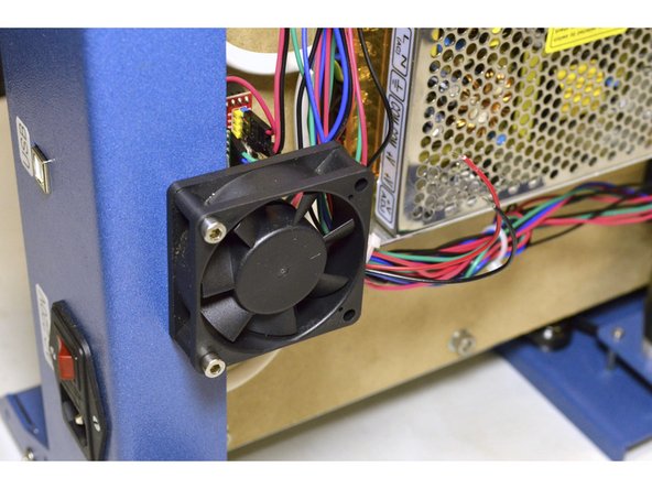 Mount the cooling fan with the sticker facing the electronics and the wires facing the power supplies