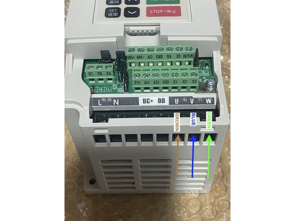 Connect the Brown, Blue and Green cable coming from the drag chain into the Electronics Assembly to the VFD. The Brown wire connects to U. The Blue wire connects to V. The Green wire connects to W.  As shown in the pictures.