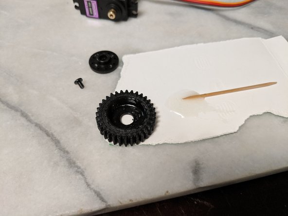 Mix up a very small amount of 2 part epoxy and spead it into the bottom center of the MainServoGear as shown in Pic 2.