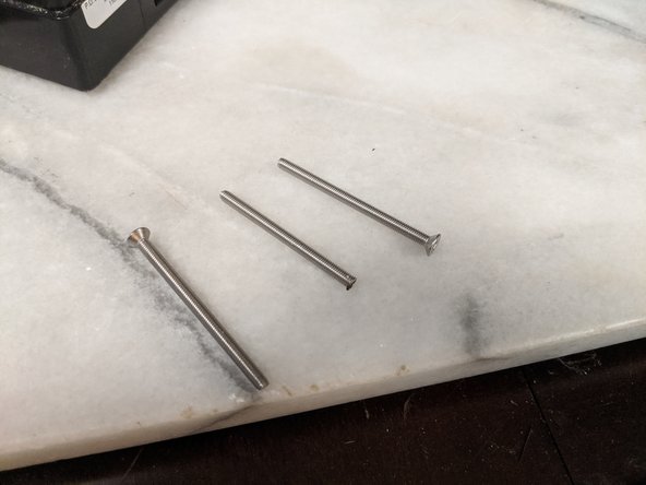 You are going to hold the screw with a pair of pliers and cut the head off the screw.  The screw will get very hot so you will want to hold it with a pair of pliers while cutting or put it in a vice.