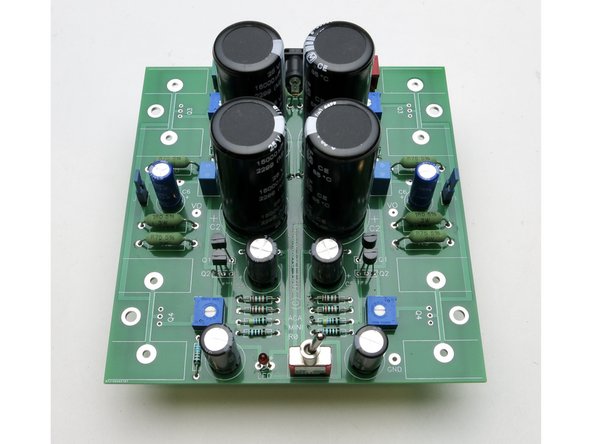 Install the large capacitors. Orient the - marks on the cans all to the inside.