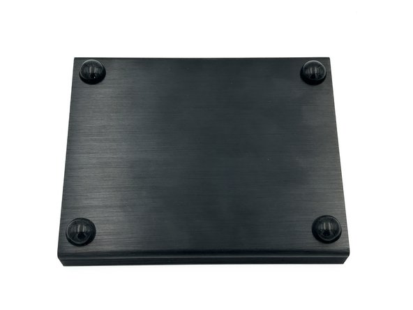 Choose one half of the clamshell chassis and install the 4, stick-on feet at each corner. Placement is not critical, but the feet should not be removed and replaced, so be careful with your alignment. The side with the feet is now the bottom of the chassis.