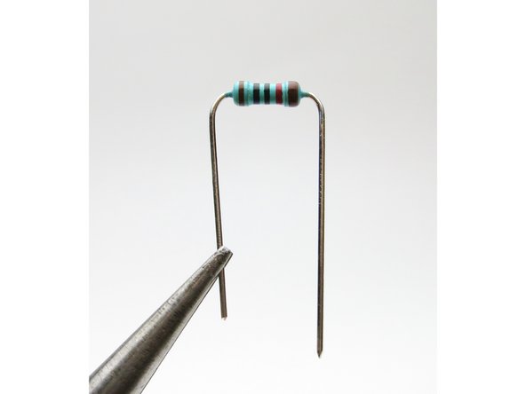 Take a resistor with the leads bent and insert it into its set of solder pads.