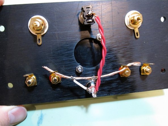 Second image: In this photo you can see that the top tab of the barrel is soldered to the buss wire. The outside connector of the barrel (PSU ground voltage) is connected to the the buss via the small white wire. PSU + voltage from the power brick is connected from the barrel pin to the center of the switch via the red wire...