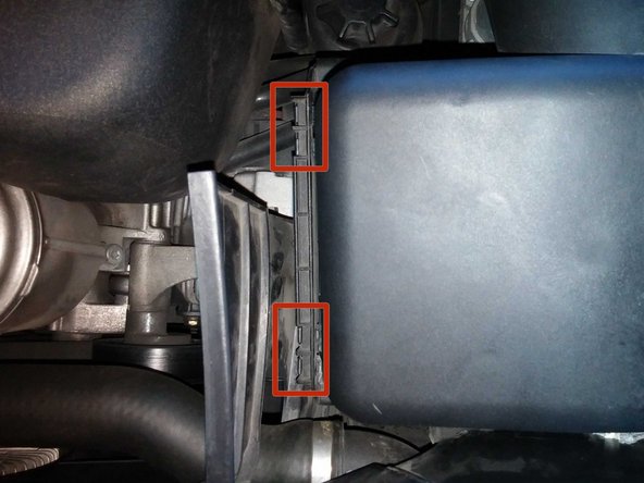 Identify the two plastic clips on the left side of the box. These clips consist of small plastic hooks on the lid hooked into square holes attached to the base.