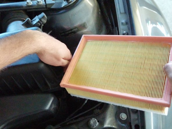 Take the new air filter and, while gently lifting the air box lid, slide the new air filter in until it seats flat inside the box.