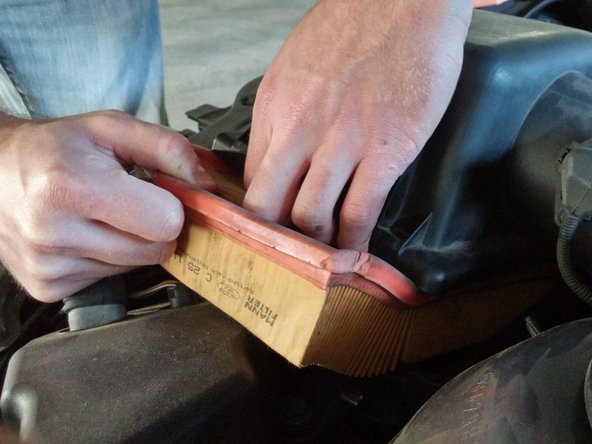 Lift the air filter up by the bright orange gasket. If you have trouble prying it up, you can gently use a flat head screwdriver for help.